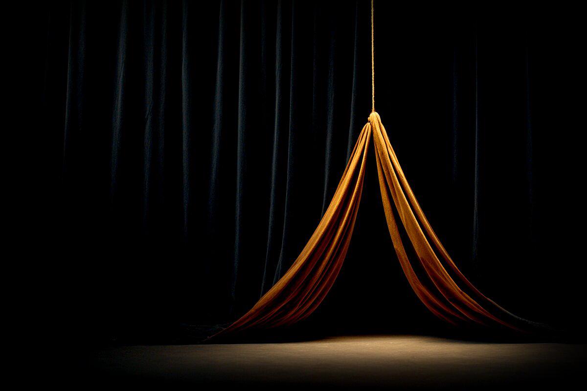 Un abito ambrato tirato da un filo su un palcoscenico vuoto - il costume che danza senza nessuno dentro